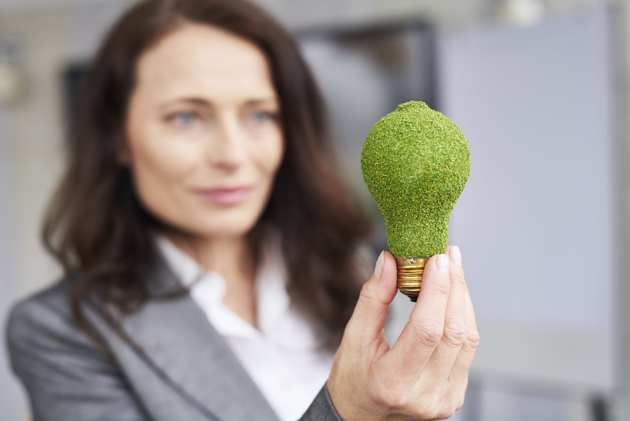 Woman holding green light bulb - renewable energy sales concept